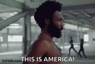 A Shirtless Man With A Beard Is Standing In Front Of A Group Of People . GIF