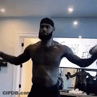 A Shirtless Man With A Beard Is Standing In Front Of A Mirror In A Gym . GIF
