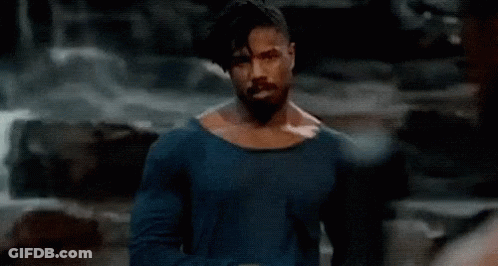 A Shirtless Man With A Beard Is Standing In Front Of A Waterfall In A Cave . GIF