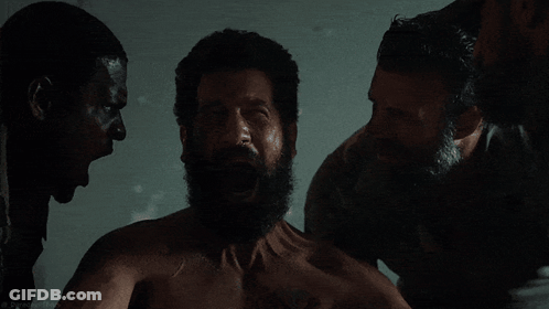A Shirtless Man With A Beard Is Surrounded By Two Men GIF