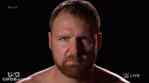 A Shirtless Man With A Beard Looks At The Camera With A USA Logo In The Background GIF