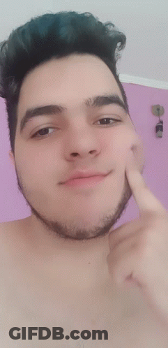 A Shirtless Man With A Beard Points To His Face With His Finger GIF