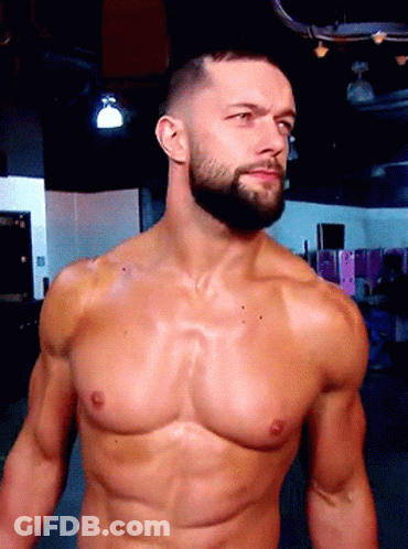 A Shirtless Man With A Beard Stands In A Dark Room GIF