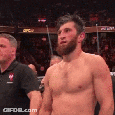 A Shirtless Man With A Beard Stands In Front Of A Crowd In A Boxing Ring . GIF