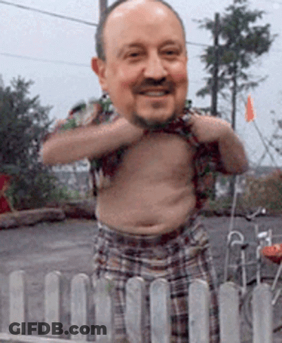 A Shirtless Man With A Big Head Is Standing Behind A Fence GIF