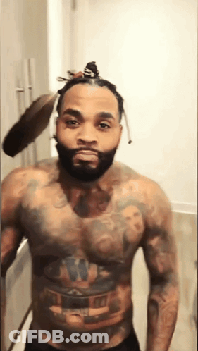 A Shirtless Man With A Bun On His Head Has A Tattoo On His Chest GIF