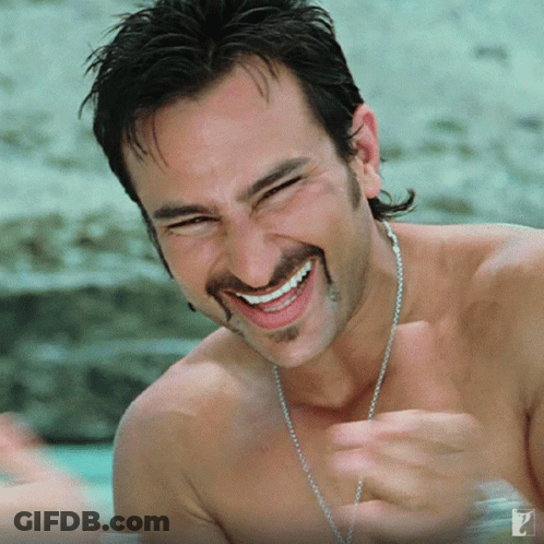 A Shirtless Man With A Chain Around His Neck Smiles For The Camera GIF