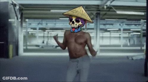 A Shirtless Man With A Colorful Skull On His Face Wearing A Conical Hat GIF