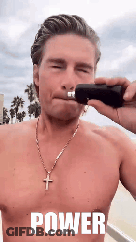 A Shirtless Man With A Cross Necklace Is Holding A Bottle In His Hand With The Word Power Written On It GIF
