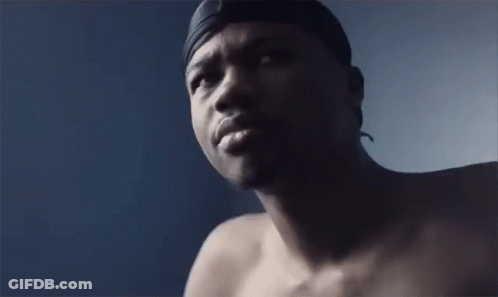 A Shirtless Man With A Headband On His Head Looks At The Camera . GIF