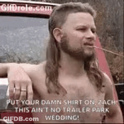 A Shirtless Man With A Mullet And A Beard Is Smoking A Cigarette In Front Of A Car . GIF