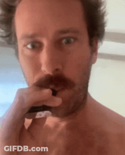 A Shirtless Man With A Mustache Is Brushing His Teeth With A Toothbrush GIF