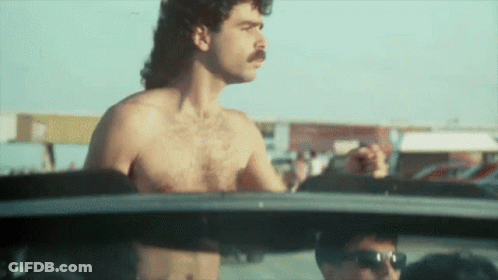 A Shirtless Man With A Mustache Is Driving A Car .. GIF