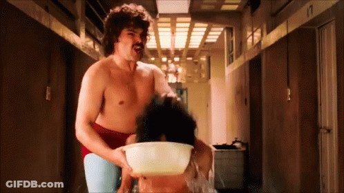 A Shirtless Man With A Mustache Is Holding A Bowl Of Water Over A Woman 'S Head GIF
