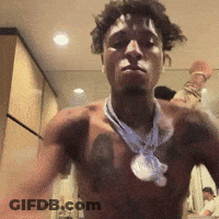 A Shirtless Man With A Necklace Around His Neck Stands In Front Of A Mirror GIF