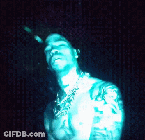 A Shirtless Man With A Tattoo On His Arm Is Lit Up In Blue Light GIF