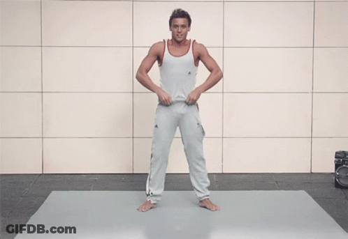 A Shirtless Man With A Tattoo On His Arm Stands On A Mat GIF