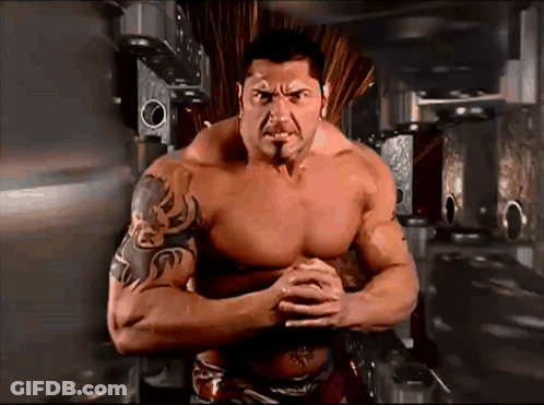 A Shirtless Man With A Tattoo On His Arm Stands With His Arms Crossed GIF