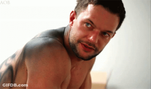 A Shirtless Man With A Tattoo On His Back Looks At The Camera With The Letters Aob Behind Him GIF