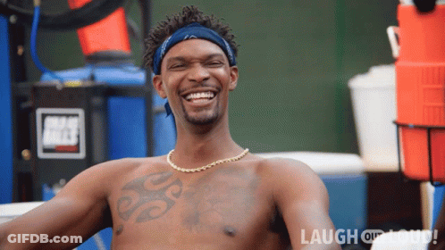 A Shirtless Man With A Tattoo On His Chest Is Smiling In Front Of A Sign That Says Laugh Or Die GIF