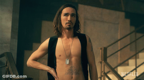A Shirtless Man With A Tattoo On His Chest Is Standing In Front Of A Netflix Sign GIF