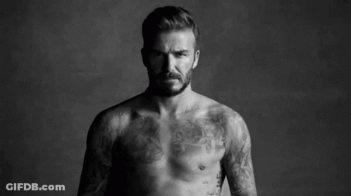 A Shirtless Man With A Tattoo On His Chest Is Standing Next To Another Shirtless Man . GIF