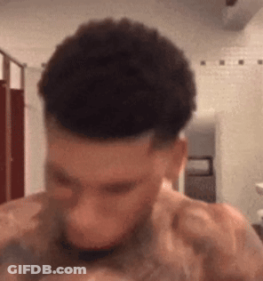 A Shirtless Man With A Tattoo On His Shoulder Is Looking Down GIF