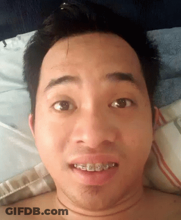 A Shirtless Man With Braces On His Teeth Is Laying On A Bed GIF