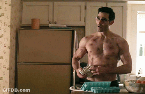 A Shirtless Man With Glasses Is Standing In Front Of A Refrigerator GIF
