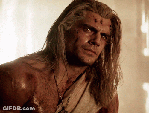 A Shirtless Man With Long Hair And A Necklace Around His Neck GIF
