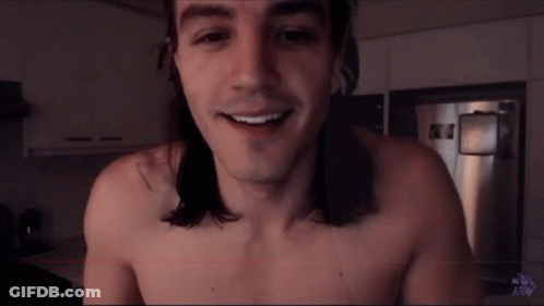 A Shirtless Man With Long Hair Smiles In A Kitchen GIF