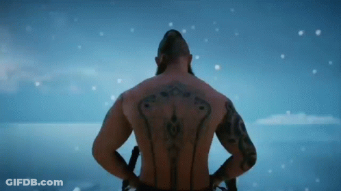 A Shirtless Man With Tattoos On His Back Is Standing In The Snow . GIF