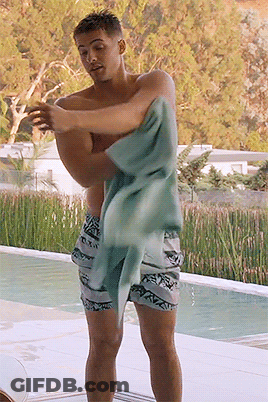 A Shirtless Man Wrapped In A Towel Stands By A Pool GIF