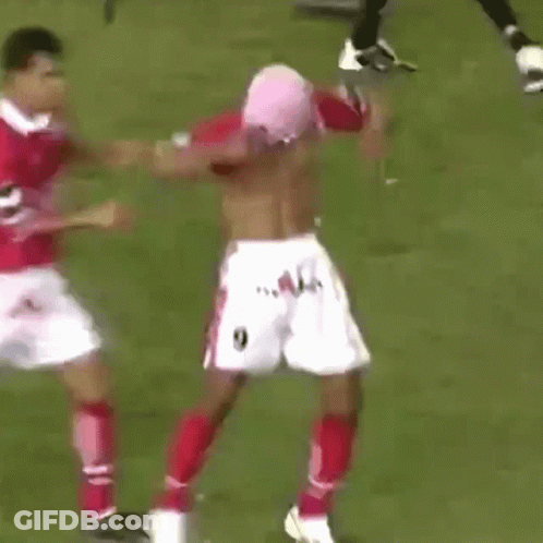 A Shirtless Soccer Player Is Being Tackled By Another Soccer Player GIF