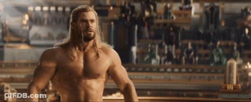 A Shirtless Thor Is Standing In Front Of A Crowd Of People GIF