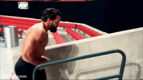 A Shirtless Wrestler Climbs Stairs In Front Of A Sign That Says Aew On It GIF