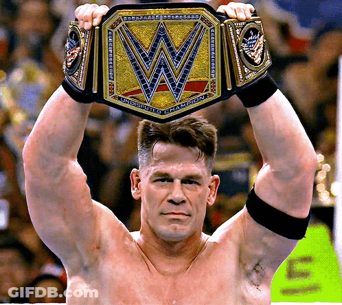 A Shirtless Wrestler Holds Up A Wrestling Championship Belt With The Letter W On It GIF
