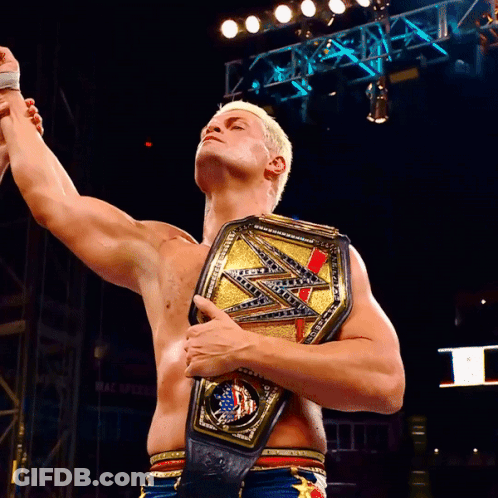 A Shirtless Wrestler Holds Up His Arms While Holding A WWE Championship Belt GIF