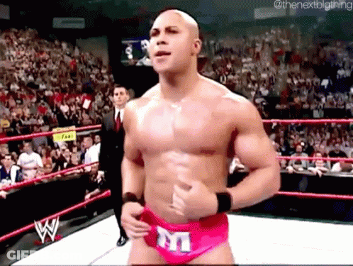 A Shirtless Wrestler In A Pink Underwear With The Letter M On It Is In A Wrestling Ring . GIF