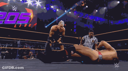 A Shirtless Wrestler In A Wrestling Ring With The Hashtag # 205Live On The Screen GIF