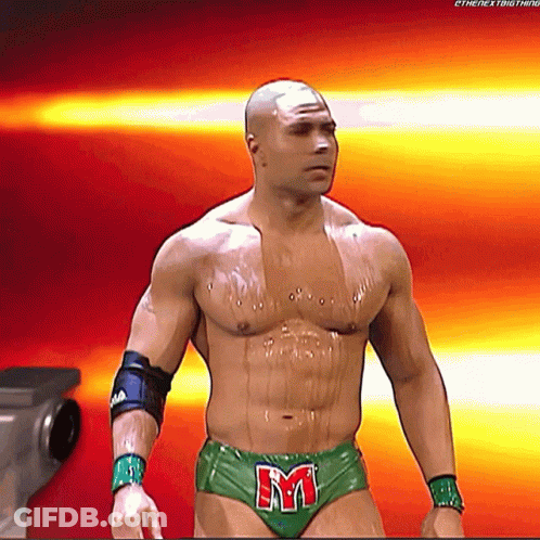 A Shirtless Wrestler In Green Underwear With The Letter M On His Belt GIF