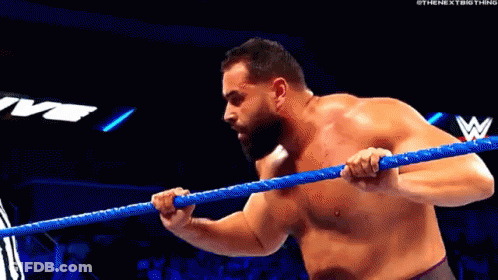 A Shirtless Wrestler Is Holding A Blue Rope In A Ring . GIF