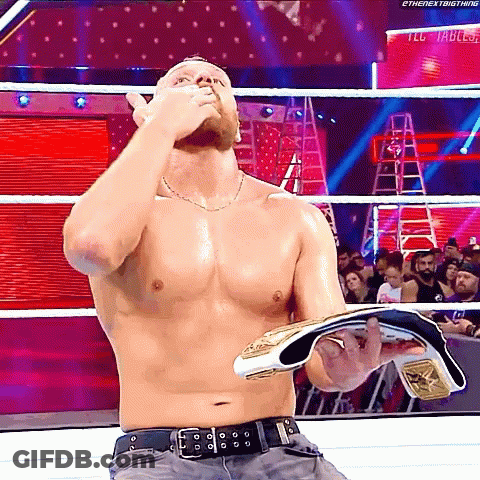A Shirtless Wrestler Is Holding A Championship Belt In A Ring GIF