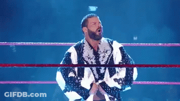A Shirtless Wrestler Is In A Wrestling Ring With His Arms Outstretched . GIF