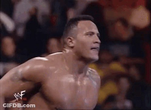A Shirtless Wrestler Is Jumping In The Air During A Match In Front Of A Crowd . GIF