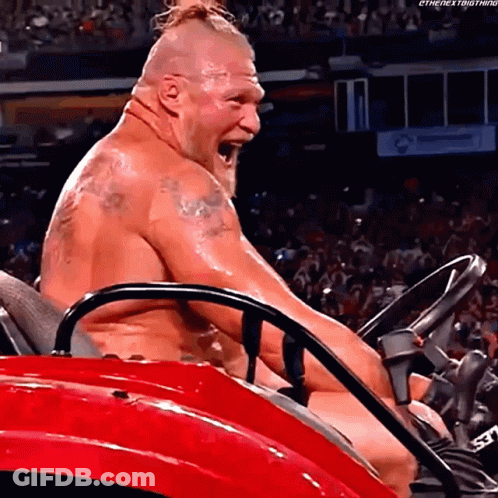 A Shirtless Wrestler Is Sitting In A Red Lawn Mower With His Mouth Open . GIF