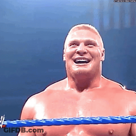 A Shirtless Wrestler Is Smiling In A Wrestling Ring With A Blue Rope . GIF