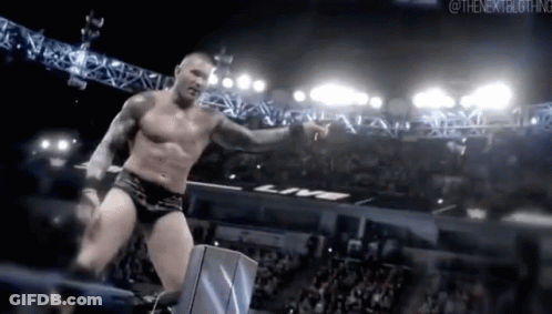 A Shirtless Wrestler Is Standing In A Ring With A Crowd Watching . GIF