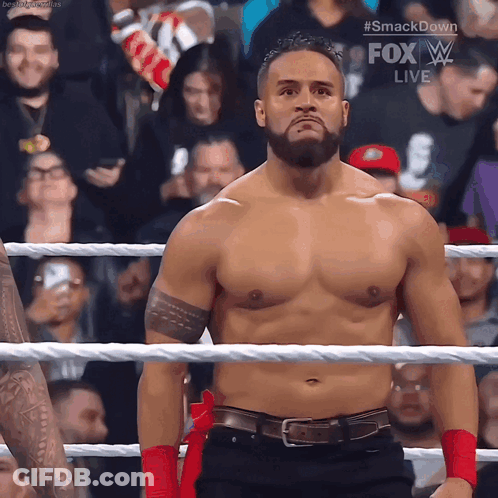 A Shirtless Wrestler Is Standing In A Ring With A Fox Live Advertisement Behind Him GIF