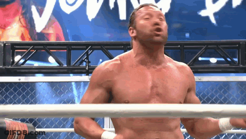 A Shirtless Wrestler Is Standing In A Ring With A Sign Behind Him That Says ' Young ' GIF